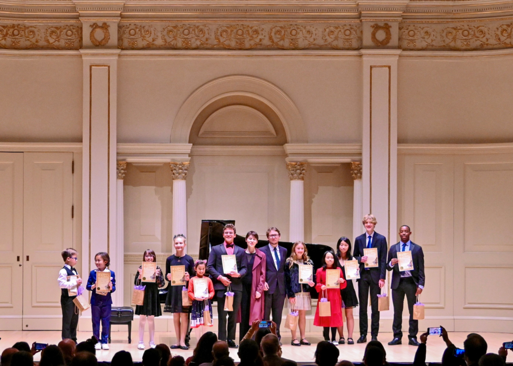 piano students gathered on stage for a photo