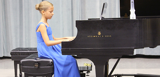 Student performing on the piano at a recital