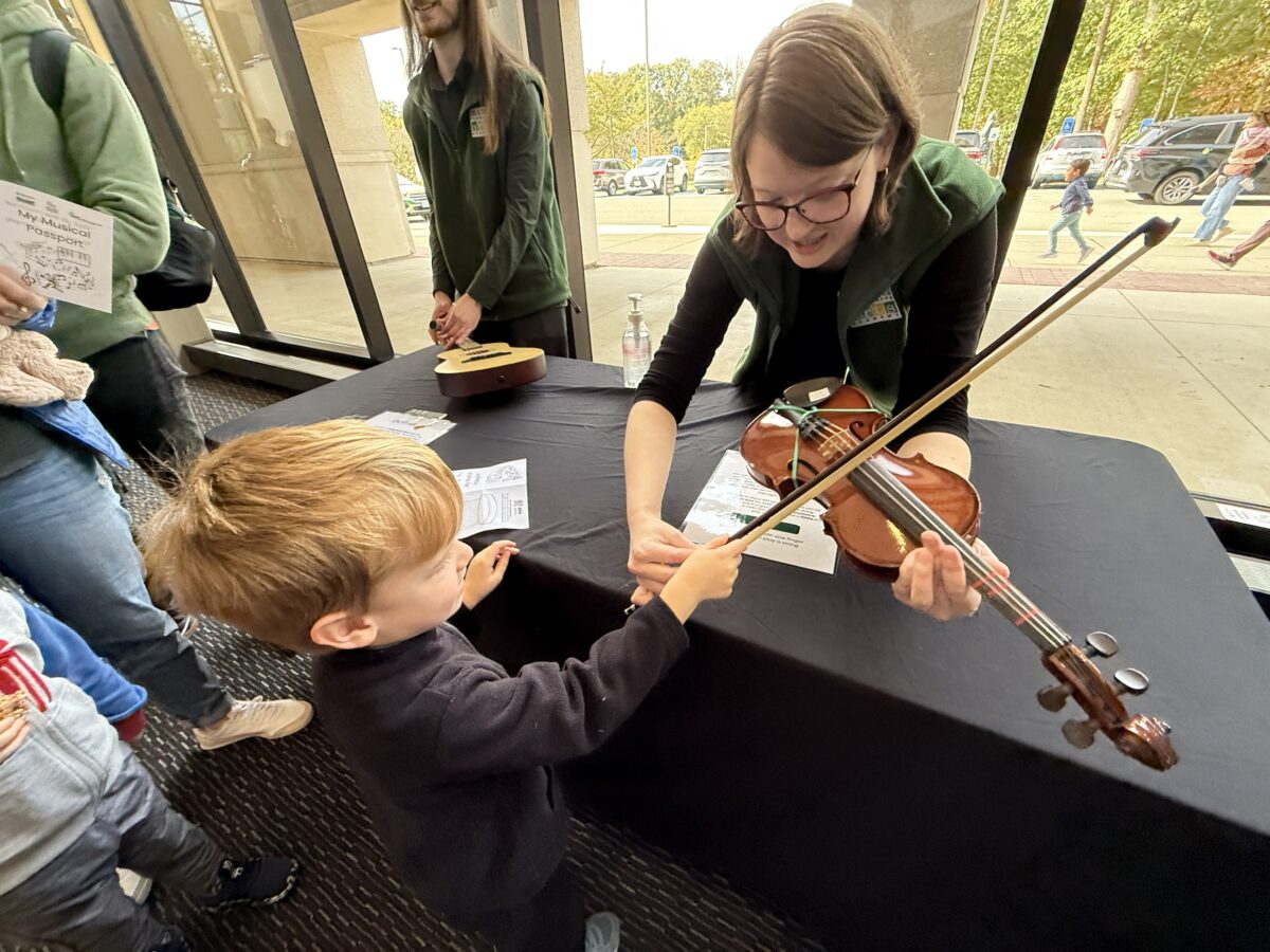MCAA staff member teaching a child about the violin