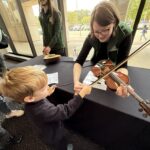 MCAA staff member teaching a child about the violin
